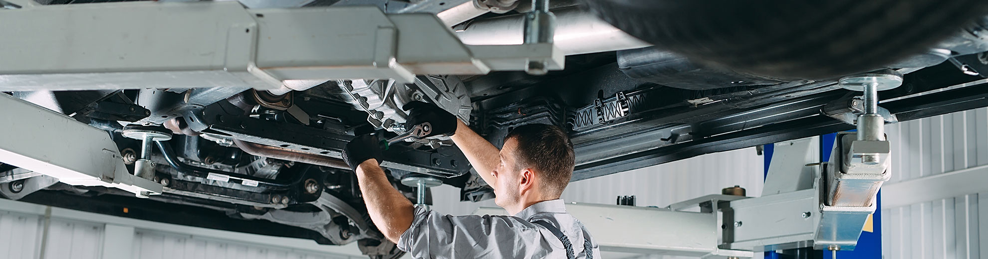 Mechanikas dirba po ant keltuvo pakelto automobiliu